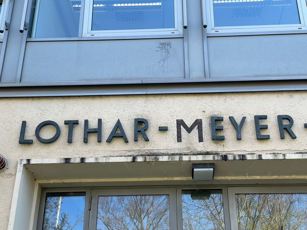 sign reading 'Lothar Meyer' in block letters, where the M block is missing and has been drawn in with paint